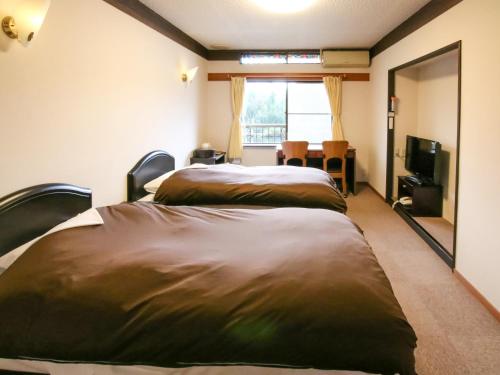 由布市金鳞湖丰国度假村的配有窗户和电视的客房内的两张床
