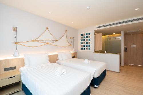 攀瓦海滩Panwaburi Beachfront Resort - SHA Extra Plus的配有白色床单的酒店客房内的两张床