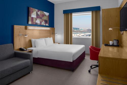 迪拜迪拜国际机场快捷假日酒店的酒店的客房 - 带一张床、椅子和窗户