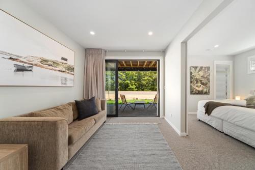 陶波Lake Luxe - Taupo的一间带沙发、床和窗户的卧室