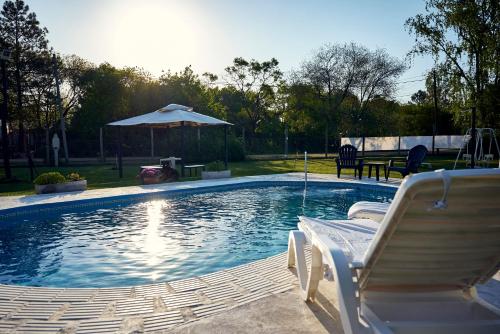 乌拉圭河畔康塞普西翁El Rubicón (casa de campo)的一个带两把椅子和遮阳伞的游泳池