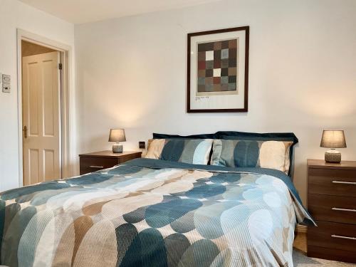 圣美伦8 Oakridge, St Mellion的一间卧室配有一张带2个床头柜和2盏灯的床。