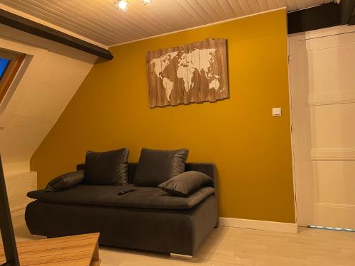 OutreauLe petit paradis的客厅配有沙发,靠着黄色的墙壁