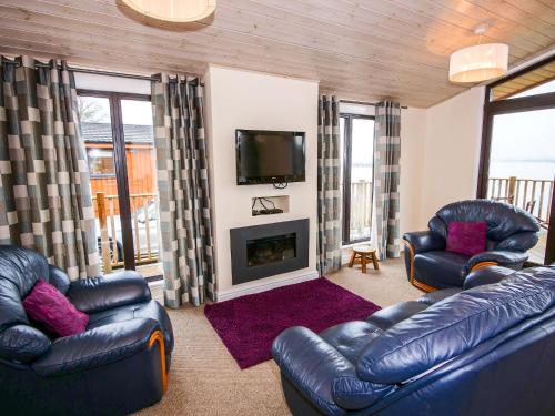 BallingryChalet Loch Leven Lodge by Interhome的客厅配有两张真皮沙发和一台电视机