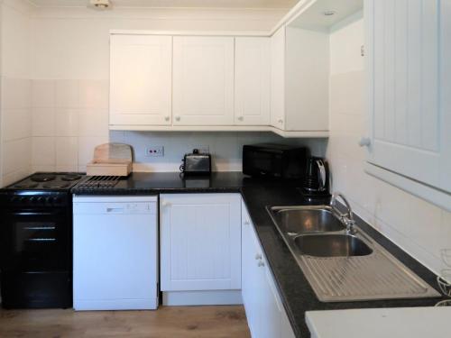ShermanburyHoliday Home Woodhouse-6 by Interhome的厨房配有白色橱柜、水槽和微波炉
