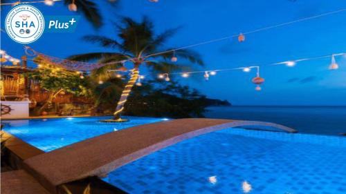 涛岛Fisherman Koh Tao的游泳池在晚上有棕榈树和灯光