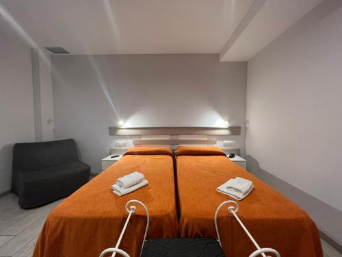 卡里拉Apartamentos Comfort Calella的一间卧室配有带橙色床单和椅子的床