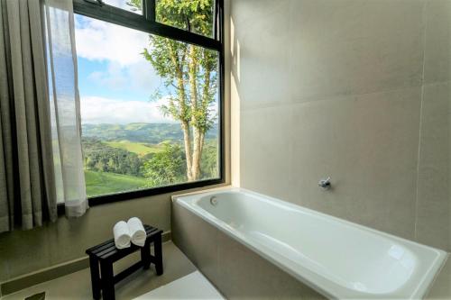 库尼亚Pousada Casa Bambu的带浴缸的浴室和大窗户