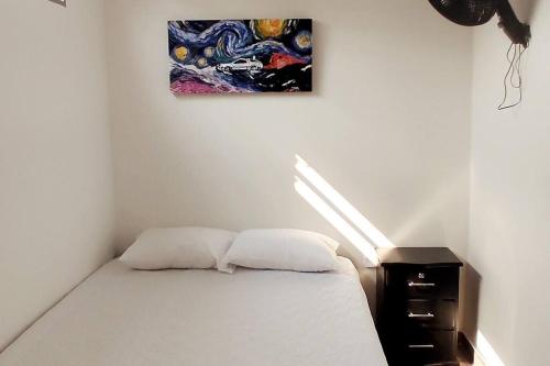 弗洛伦西亚Hermoso apartamento con servicios y garaje.的卧室配有一张床,墙上挂有绘画作品