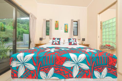 拉罗汤加Cook Islands Holiday Villas-Tuoro Holiday的一间卧室配有一张大床和色彩缤纷的被子