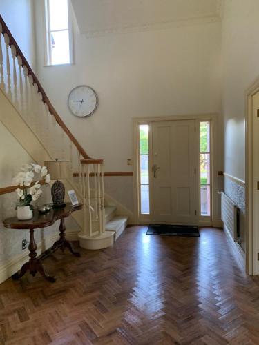 北帕默斯顿Pin Oaks Luxury Bed & Breakfast的客厅设有楼梯和墙上的时钟