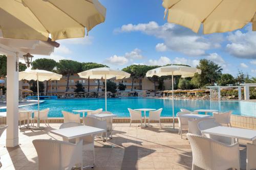 卡拉·利贝罗托Tirreno Resort的一个带桌椅和遮阳伞的游泳池