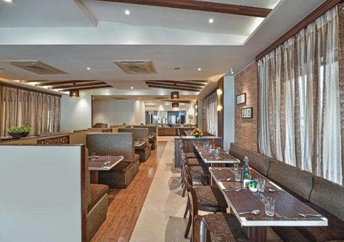 罗纳瓦拉Meritas Crystal Resort的一间带桌子和沙发的餐厅以及一间酒吧