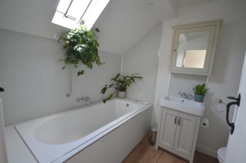 查格福德Arch Cottage的带浴缸、水槽和镜子的浴室