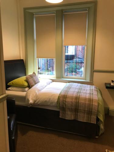 卡莱尔Abberley House的一间卧室配有一张带两个窗户的床