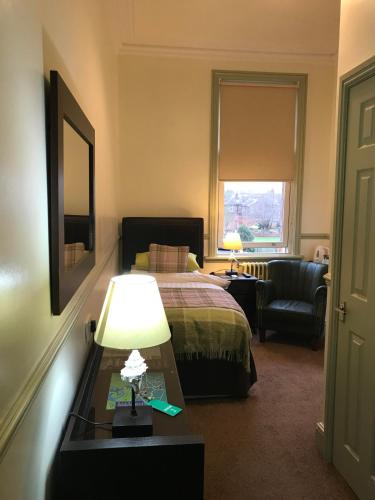 卡莱尔Abberley House的酒店客房配有一张床和一张带台灯的桌子
