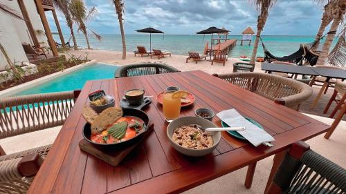 图卢姆Nerea Tulum的一张木桌,上面放着一碗食物和海滩上的饮料