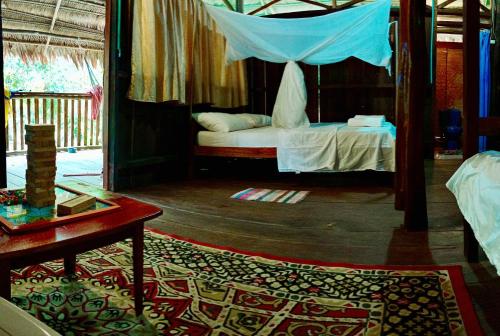 莱蒂西亚Bungalow In The Jungle -Ecolodge HUITOTO的一间卧室配有一张带天蓬和桌子的床