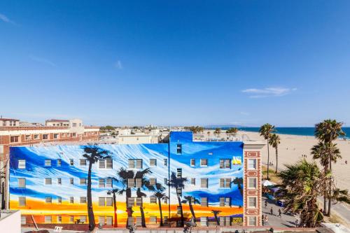 洛杉矶威尼斯套房酒店的一座拥有棕榈树和海滩的蓝色建筑