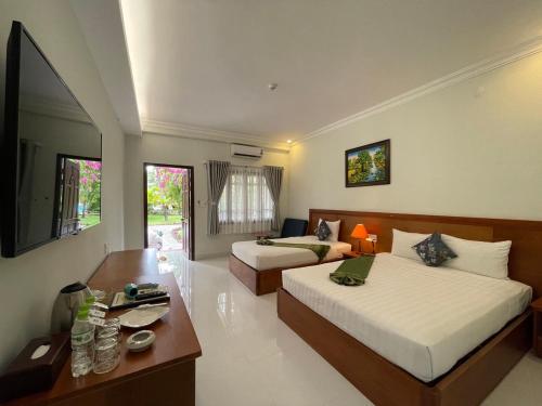 美奈Four Oceans Beach Resort - Bon Bien Mui Ne的酒店客房带两张床、书桌以及一间客房。