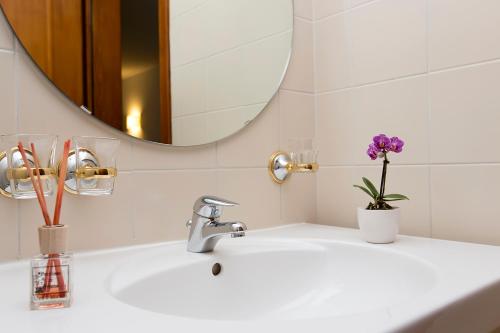博斯克古林瓦尔泽餐厅酒店的浴室水槽设有镜子和紫色花卉花瓶