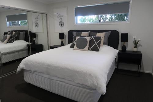ParrearraSunshine Coast Beach House - 2 mins to beach的卧室设有一张白色大床和两个窗户。