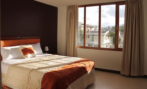Machachi萨基瓦酒店的一间卧室设有一张床和一个大窗户