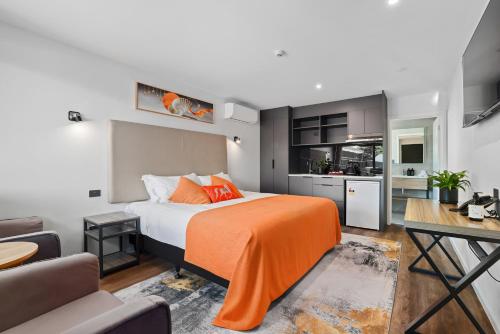 基督城Golden Hotel的一间卧室配有一张带橙色毯子的床