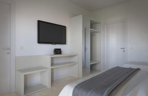 里米尼Hotel Aron的一间白色卧室,墙上配有电视