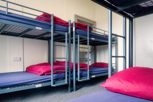 爱丁堡Princes Street Hostel的带3张双层床和红色枕头的客房