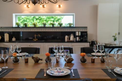 迪尔森-斯托科姆Tussen Hemel en Maas的一张长木桌子,上面有玻璃杯和盘子