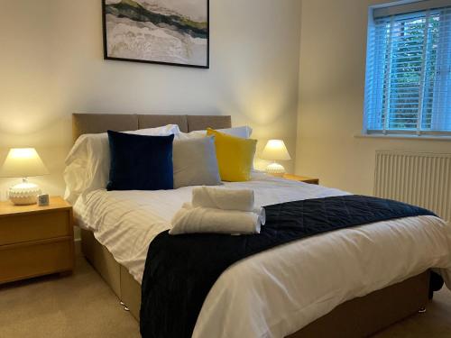 埃格姆Modern 2 Bed Apt in Egham High Street, with private parking and Wifi的一间卧室配有一张带蓝色和黄色枕头的大床