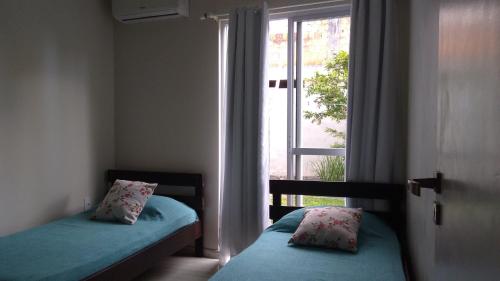 弗洛里亚诺波利斯Casas Adilio Florianopolis-norte的一间卧室设有两张单人床和一个窗户。