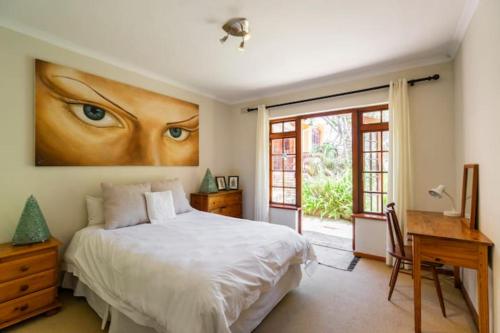 豪特湾Unique Hout Bay House的一间卧室配有一张床、一张书桌和一个窗户。