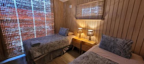 百内三塔Cabaña en Laguna Azul Patagonia Bagual的一间小卧室,配有两张床和窗户