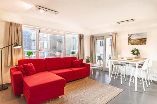 奥斯坦德Las Dunas - 30m van het strand的客厅配有红色的沙发和桌子