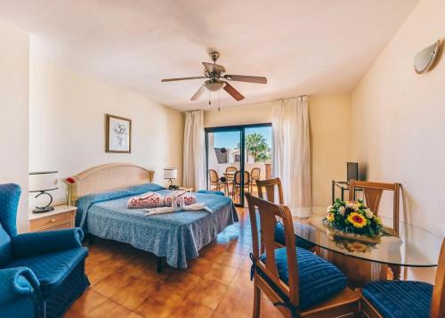 圣米格尔德阿沃纳Sunshine Apartments的卧室配有一张床和一张桌子及椅子