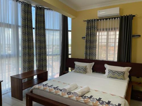 穆龙达瓦Havana Hôtel的一间卧室配有一张大床、窗帘和窗户。