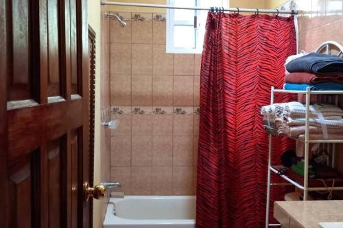 Crooked TreeRoyal Properties Link的一间带红色淋浴帘和浴缸的浴室