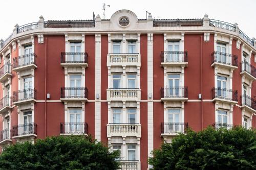 瓦伦西亚鲁发法高科技酒店的一座红色的建筑,设有阳台,前面有树木