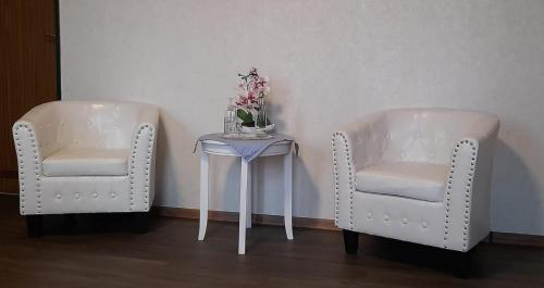 马林哈弗Landgasthof Hotel Zur Waage的两把白色的椅子和一张带鲜花的桌子