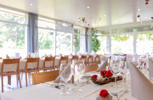 艾因西德伦Hotel Allegro Einsiedeln的用餐室配有带玻璃杯和玫瑰的桌子