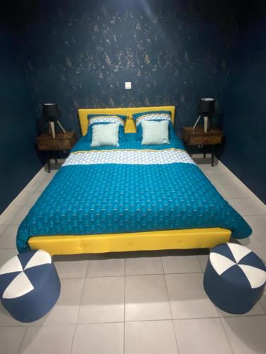RinxentGîte de la Prévosserie的一张蓝色和黄色的床,房间设有两张桌子