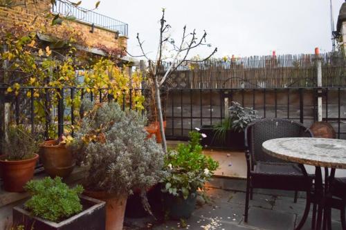 伦敦Stylish and Spacious Apartment with Terrace的一个带桌子和盆栽的庭院和围栏