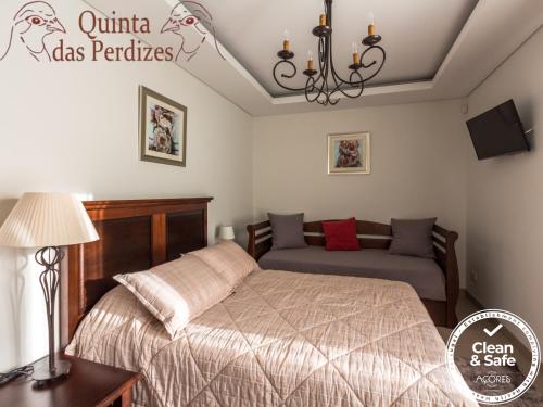 蓬塔德尔加达Quinta das Perdizes的一间卧室配有一张床和一张沙发