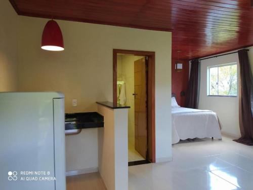 拉夫拉斯诺瓦斯Suites Cantinho de MInas的客房设有带一张床和一台冰箱的卧室。