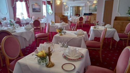 锡德茅斯里维埃拉酒店的用餐室配有白色桌子和粉红色椅子