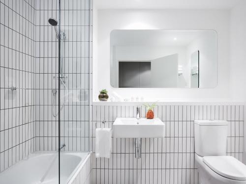 墨尔本艺术系列 - 拉威尔一室公寓 的浴室配有卫生间、盥洗盆和浴缸。