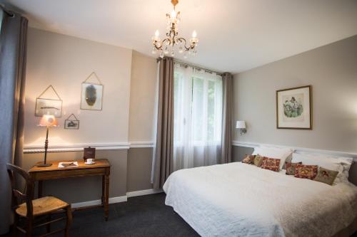Bresson沙凡特餐厅酒店的一间卧室配有一张床、一张桌子和一个吊灯。