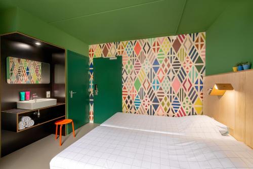 多德雷赫特Stayokay Hostel Dordrecht - Nationaal Park De Biesbosch的卧室配有白色的床和色彩缤纷的墙壁